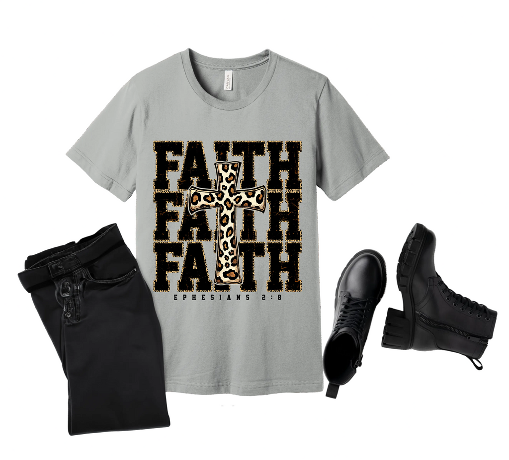Gray t-shirt with 'FAITH' text and cross design on a wooden surface with black pants and boots.