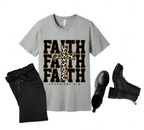 Gray t-shirt with 'FAITH' text and cross design on a wooden surface with black pants and boots.