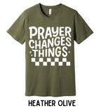 Green t-shirt with 'PRAYER CHANGES THINGS' text on a wooden background