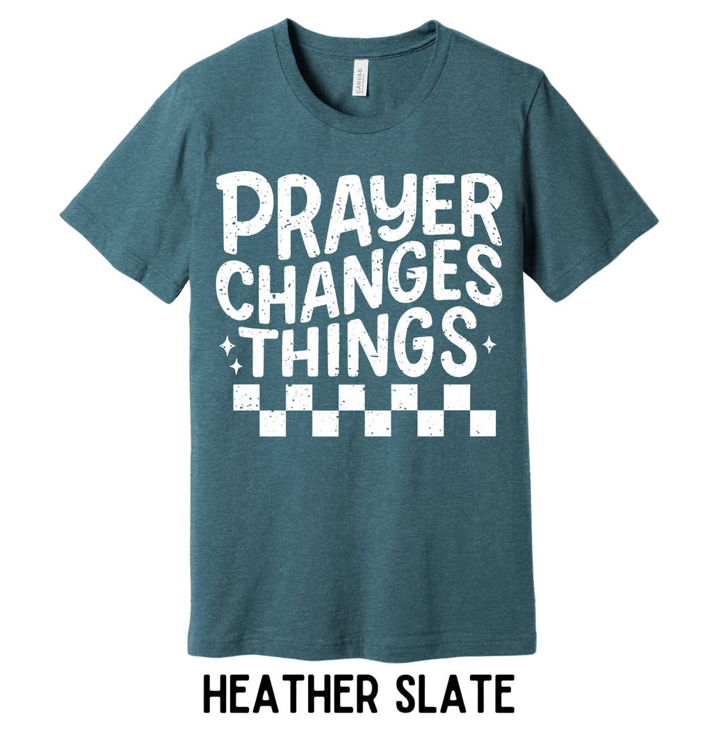 Heather slate t-shirt with 'PRAYER CHANGES THINGS' text on a wooden background