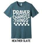 Heather slate t-shirt with 'PRAYER CHANGES THINGS' text on a wooden background