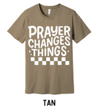 Tan t-shirt with 'PRAYER CHANGES THINGS' text on a wooden background